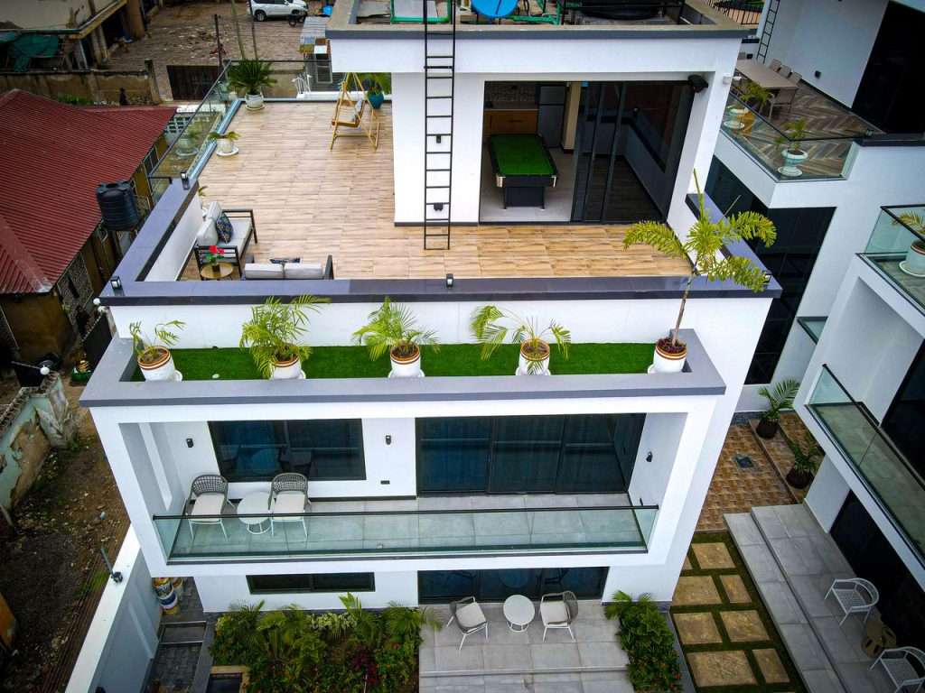 Aerial view of a modern white house with a rooftop terrace and swimming pool