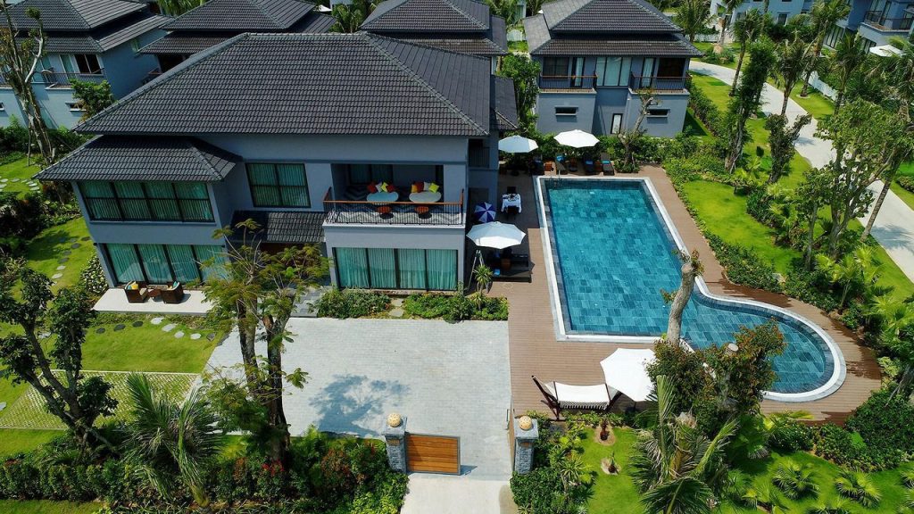 Aerial view of a villa with a swimming pool surrounded by tropical garden