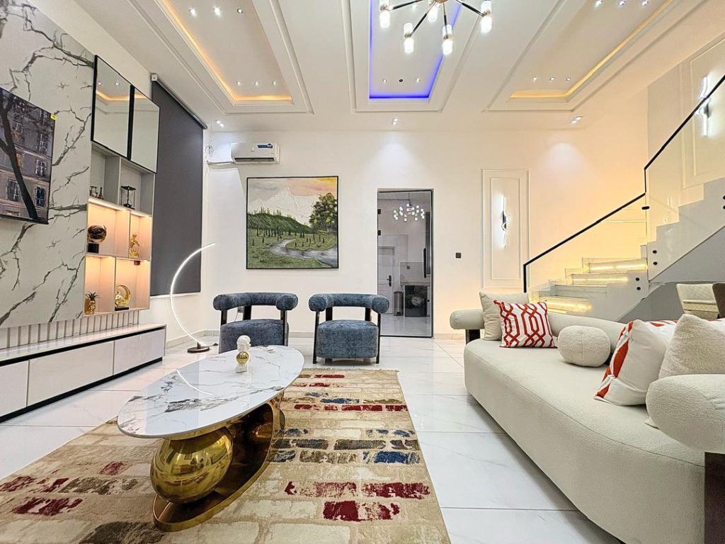 Living area of a Lagos short-let with a sofa, gold coffee table, marble feature wall and open staircase